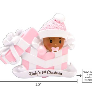 Puede incluir: Adorno navide&ntilde;o rosa y blanco con una ni&ntilde;a beb&eacute; con un gorro rosa y una caja de regalo rosa y blanca. El adorno mide 2,75 pulgadas de alto y 3,5 pulgadas de ancho. El texto "Baby's 1st Christmas" est&aacute; impreso en el adorno.