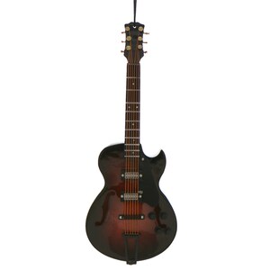 May include: A miniature acoustic guitar ornament with a black and brown finish. The guitar has a detailed design, including strings, frets, and tuning pegs. A black string is attached for hanging.