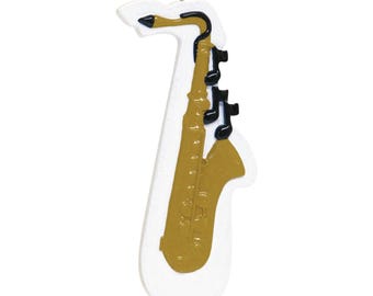 May include: A gold-colored saxophone ornament with black musical notes. The ornament is white and has a loop for hanging.