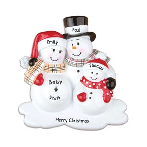 May include: A white snowman family Christmas ornament with red, white and black accents. The snowman on the left is a pregnant woman with the name "Emily" written on her hat. The snowman in the middle is a man with the name "Paul" written on his hat. The snowman on the right is a child with the name "Thomas" written on his hat. The ornament also includes the text "Baby Scott" and "Merry Christmas".