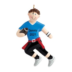 May include: A personalised Christmas bauble depicting a cartoon boy wearing a blue jersey and black trousers, holding a football. The jersey has the name "Dennis" and the year "2021" printed on it.