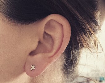 May include: A close-up of a person's ear with a small gold cross earring.