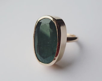 Stor oval ring med grön ädelsten, 9 karat gult guld, besättning