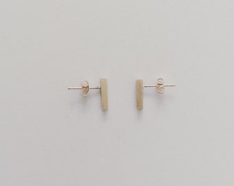 May include: A pair of silver bar stud earrings. The earrings are simple and minimalist, with a rectangular shape.