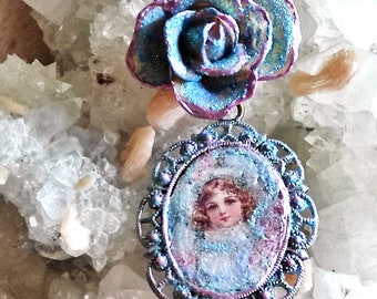 Collier Anaïs petite fille Shabby chic en rose et bleu, l'enfant est entourée de roses et de myosotis avec une rose bleue ourlée de rose