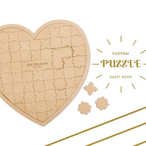 May include: A heart-shaped wooden puzzle with a personalized inscription "THE NELSONS 16.12.2023". The puzzle is designed as a guest book, with the text "CUSTOM PUZZLE GUEST BOOK" printed below the heart.