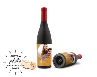 May include: Black wine bottle-shaped corkscrew with a red top. The bottle features a custom photo label with a couple. A cork and another corkscrew are also visible. Text on the label reads "Mary & Finn" and a date.