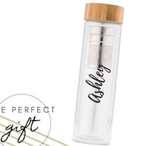 Op de afbeelding: Een glazen theefles met een bamboe deksel en een roestvrijstalen infuser. De fles heeft de naam "Ashley" in het zwart erop.