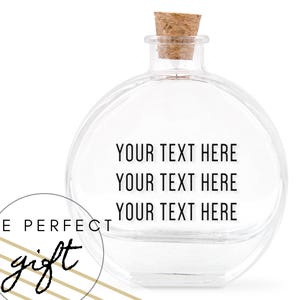 Könnte beinhalten: Eine klare, runde Glasflasche mit einem Korken. Die Flasche hat den Text "YOUR TEXT HERE" dreimal wiederholt. Eine kreisförmige Grafik mit den Worten "THE PERFECT gift" befindet sich in der unteren linken Ecke.