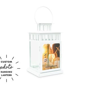 May include: A white, custom photo hanging lantern with a handle. The lantern features a framed photo of two people kissing, with the text "S+W" and "SAGE & WILLOW" visible. The words "CUSTOM photo HANGING LANTERN" are also displayed.