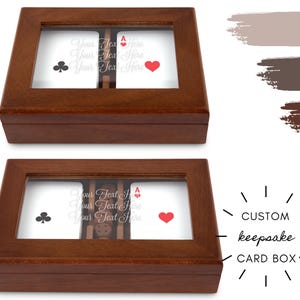Peut inclure: Deux boîtes à cartes souvenirs en bois avec des dessus en verre. Chaque boîte affiche des cartes à jouer avec un symbole de trèfle et de cœur. Le texte "Your Text Here" est visible sur les cartes. Les boîtes sont étiquetées "CUSTOM keepsake CARD BOX".