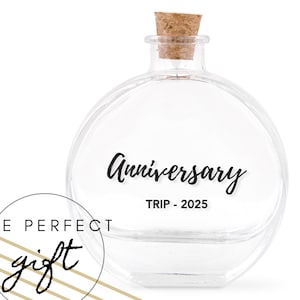 Peut inclure: Une bouteille en verre transparente et ronde avec un bouchon en liège. Le mot "Anniversary" et "TRIP - 2025" sont imprimés en noir sur la bouteille. Un graphique circulaire avec les mots "THE PERFECT gift" est dans le coin inférieur gauche.