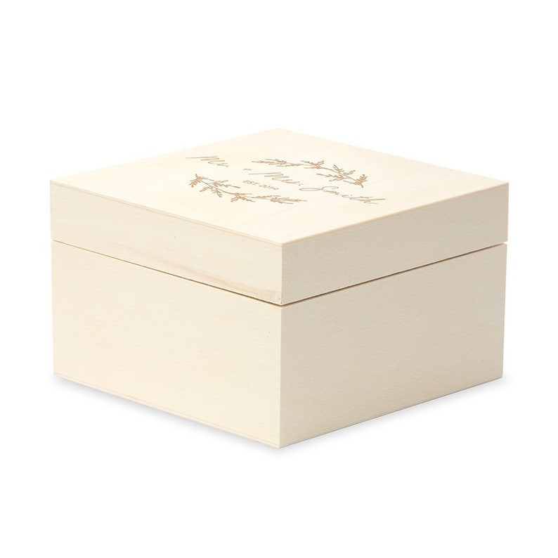 May include: A white wooden box with a gold inscription that reads "Mr. & Mrs. Smith Established 2023" with a floral wreath design.