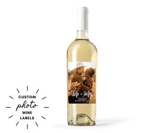 May include: A clear wine bottle with a white label featuring a photo of a couple. The label reads "Mr + Mrs" with a date. Text on the left says "CUSTOM photo WINE LABELS".