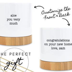 Op de afbeelding: Witte keramische plantenpot met een bamboe basis. Op de ene pot staat "aloe you very much", en op de andere staat "gefeliciteerd met je nieuwe huis love, sam". De tekst "THE PERFECT gift" is ook zichtbaar.