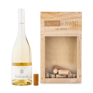 May include: A wooden box with a glass front, labelled "Uncork & Unwind The Smiths", containing a collection of wine corks. A bottle of white wine and a single cork are also pictured.