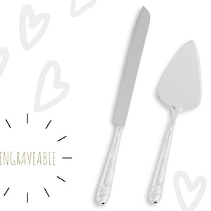 May include: A set of two silver cake knives with engraved handles. The knives are designed for cutting wedding cake. The text "ENGRAVEABLE" is visible on the image.