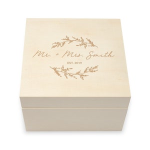 May include: A light wood box with a lid, engraved with the text "Mr. + Mrs. Smith EST. 2019" and a floral design.