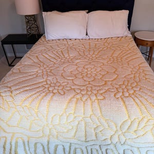 May include: A white and yellow bedspread with a floral pattern. The bedspread is made of a soft, plush material and has a raised design.