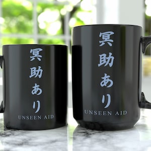 Puede incluir: Dos tazas de café negras con el texto "UNSEEN AID" y caracteres japoneses que se traducen como "Ayuda invisible".