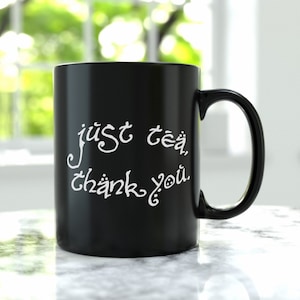 Peut inclure: Mug en céramique noire avec un texte en cursive blanche qui dit "just tea, thank you".