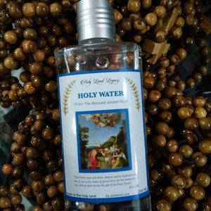 May include: A clear glass bottle with a silver cap, labelled "Holy Water" from the Blessed Jordan River. The bottle contains a clear liquid and has a small image of a religious scene on the label. The label also includes the text "Then Peter said unto them, Repent, and be baptised every one of you in the name of Jesus Christ for the remission of sins, and ye shall receive the gift of the Holy Ghost." Acts 2:38. Made in the holy land for external use. 250 ml.