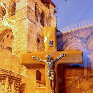 Puede incluir: Un crucifijo de madera con una figura de Jes&uacute;s de plata. El crucifijo est&aacute; delante de una imagen de Jerusal&eacute;n, Israel. La imagen muestra un edificio de piedra con arcos y una barandilla de metal.