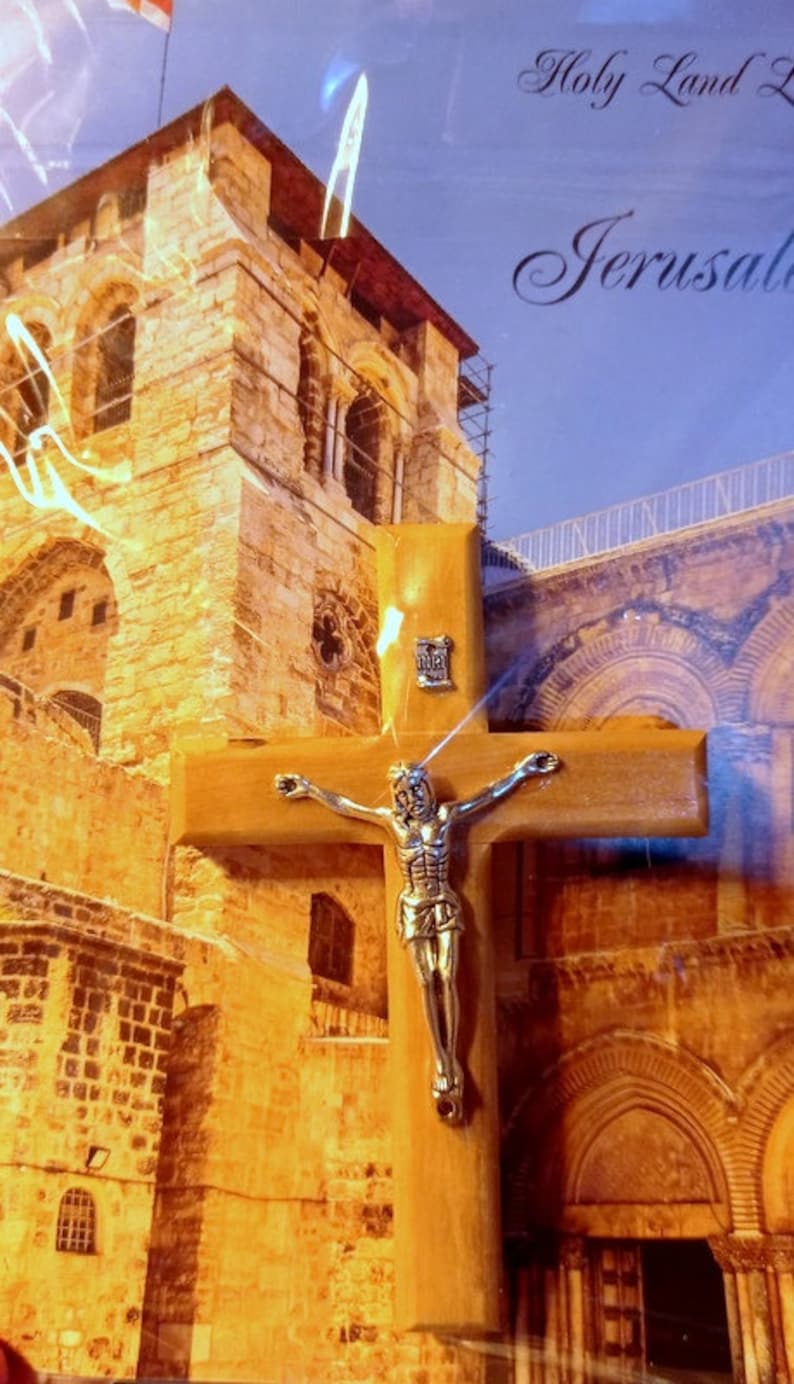 Puede incluir: Un crucifijo de madera con una figura de Jes&uacute;s de plata. El crucifijo est&aacute; delante de una imagen de Jerusal&eacute;n, Israel. La imagen muestra un edificio de piedra con arcos y una barandilla de metal.