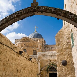 Puede incluir: Un arco de piedra con una cruz en la parte superior conduce a una vista de un edificio abovedado con una cruz en la parte superior. El edificio est&aacute; hecho de piedra y tiene una c&uacute;pula azul. El arco est&aacute; hecho de piedra y tiene un marco de madera. El arco est&aacute; decorado con tallas.