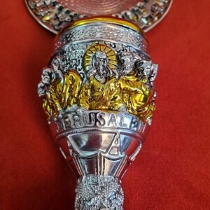 Puede incluir: C&aacute;liz de plata con detalles dorados y elaborados. El c&aacute;liz presenta una representaci&oacute;n de Jesucristo y las palabras "Jerusal&eacute;n" y "925".