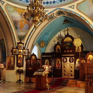 Puede incluir: El interior de una iglesia con un altar adornado con oro, candelabros ornamentados y numerosos iconos religiosos en las paredes.