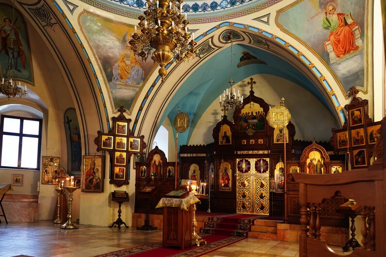 Puede incluir: El interior de una iglesia con un altar adornado con oro, candelabros ornamentados y numerosos iconos religiosos en las paredes.