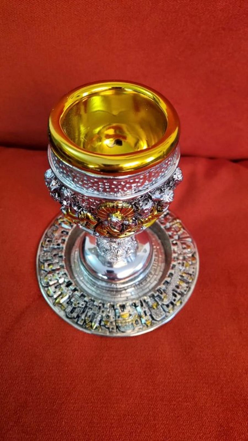 Puede incluir: Un c&aacute;liz de plata con detalles dorados y dise&ntilde;os intrincados. El c&aacute;liz tiene una base redonda y una copa con un interior dorado. El c&aacute;liz est&aacute; sobre un plato de plata con un borde dorado.