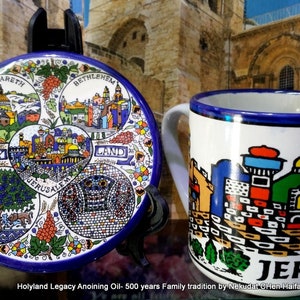 Peut inclure: Une assiette en céramique bleue et blanche avec un motif de Jérusalem, Bethléem, Nazareth et la Terre Sainte. L'assiette est sur un support noir. Une tasse en céramique bleue et blanche avec un motif de Jérusalem est à côté de l'assiette.