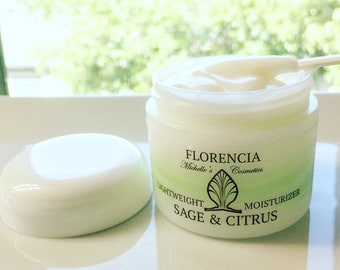 May include: A white jar with a green lid and label. The label reads "Florencia Michelle's Cosmetics Lightweight Sage & Citrus Moisturizer".