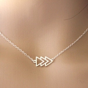 May include: A silver necklace with a delicate chain and a pendant featuring three connected triangle shapes.
