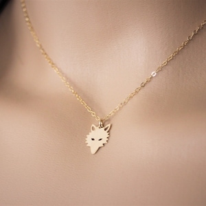 May include: A gold chain necklace with a wolf head pendant.
