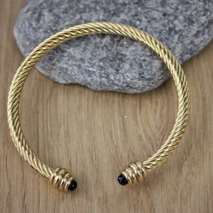 Guldfärgat vridet armband i rostfritt stål med svarta onyxstenar