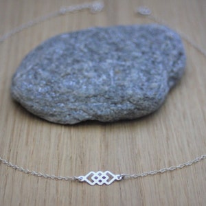 May include: A silver chain necklace featuring a delicate, geometric pendant. The pendant is crafted from interlocking squares, creating a modern and minimalist design.
