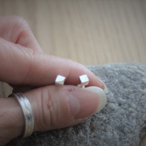 Peut inclure: Une paire de petites boucles d'oreilles en argent de forme carrée.