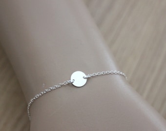 May include: A silver chain bracelet with a small, round silver charm.