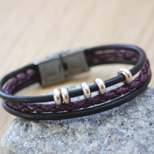 May include: A black and purple leather bracelet with silver beads and a magnetic clasp.