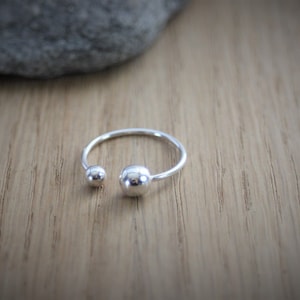 Peut inclure: Une bague en argent avec deux boules rondes à chaque extrémité.