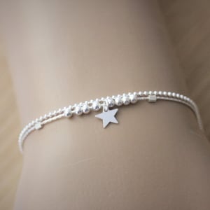 May include: A silver beaded bracelet with a star charm.
