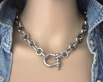 May include: A silver chain necklace with a large, silver, hook-style clasp.