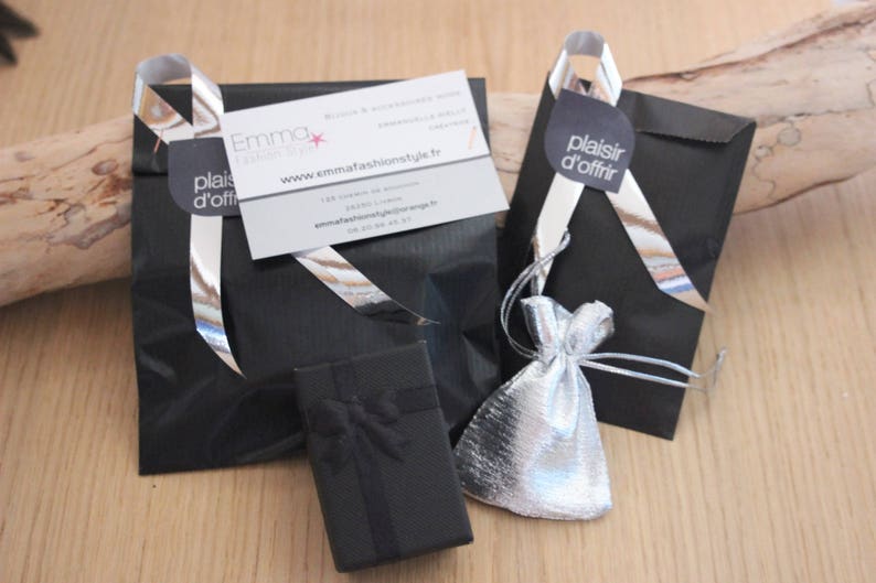 K&ouml;nnte beinhalten: Zwei schwarze Geschenkt&uuml;ten mit silbernem Band und eine kleine schwarze Box. Eine T&uuml;te hat eine wei&szlig;e Karte mit dem Text "Emma Fashion Style" und der Website-Adresse "www.emmafashionstyle.fr". Die andere T&uuml;te hat einen wei&szlig;en Kreis mit dem Text "plaisir d'offrir".