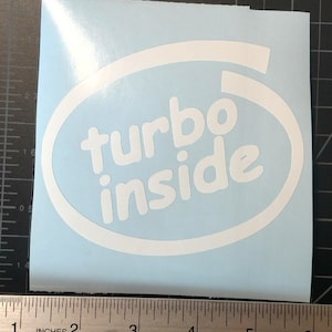 Puede incluir: Pegatina de vinilo blanco sobre fondo azul. La pegatina tiene forma ovalada y tiene el texto "turbo inside" en blanco.