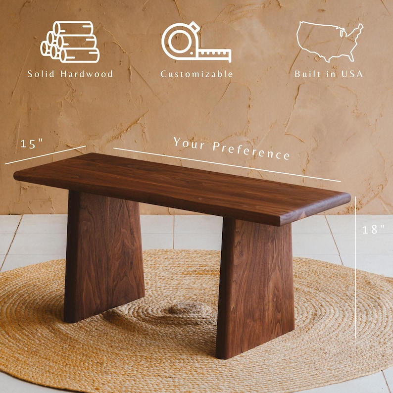 Puede incluir: Un banco de madera dura maciza de color marr&oacute;n oscuro con una parte superior rectangular y dos patas anchas y planas. El texto indica que est&aacute; fabricado en EE. UU., es personalizable y mide 38,1 cm de profundidad y 45,7 cm de alto, largo a elegir.