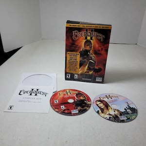 Könnte beinhalten: EverQuest II Starter Kit PC-Spiel-Boxset mit einer vertikalen Spieleverpackung mit Charakter-Artwork, zwei Spiele-Discs mit der Aufschrift Disc One und Disc Two mit Fantasy-Illustrationen sowie einer weißen Papierhülle für das Handbuch.