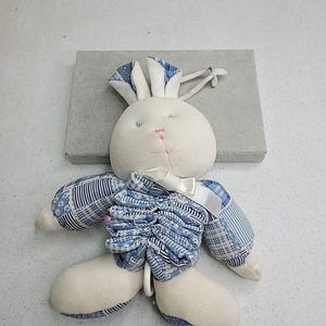 Puede incluir: Una taza de cerámica blanca con un asa negra y el texto "But First, Coffee" en negrita negra. La taza está sobre una superficie de madera. La taza mide 10 cm de alto.